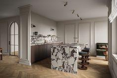 an elegant kitchen with marble counter tops and wooden flooring, along with two bar stools