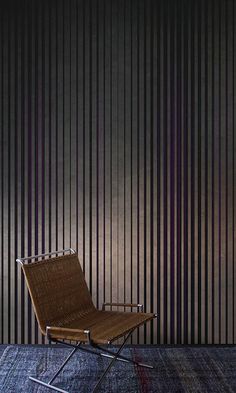 a chair sitting in front of a wall with vertical stripes on it's side