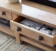 a wooden table with two drawers and some pictures on it's sideboard next to a coffee table