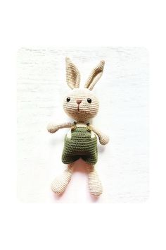 a crocheted stuffed rabbit with a green bag on it's back legs