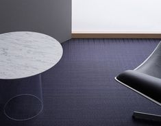 a white table sitting on top of a blue carpeted floor next to a black chair