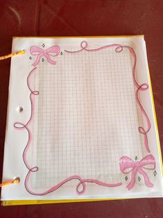 a notebook with pink ribbon on it and a pen in the middle, sitting on a table