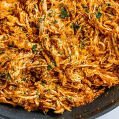 shredded chicken in a skillet with parsley on top