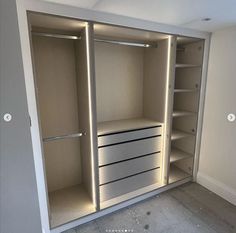 an empty room with two white drawers and shelves on each side of the closet door