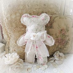 a teddy bear sitting on top of a couch next to pillows and flowers with buttons all around it