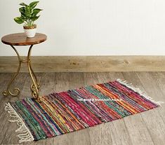 a table with a potted plant on top of it next to a colorful rug