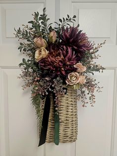 a wicker basket with flowers hanging on the front door