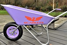 a purple wheelbarrow with the word scarlies on it sitting on a wooden deck