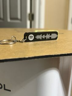 a black keychain sitting on top of a wooden table next to a door