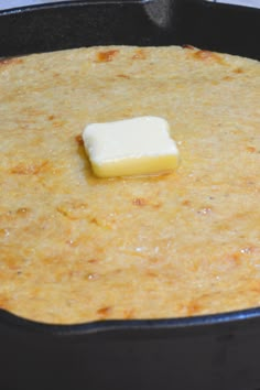 a square piece of butter sitting on top of a pan filled with batter and cheese