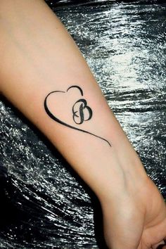 a woman's arm with a heart tattoo on it