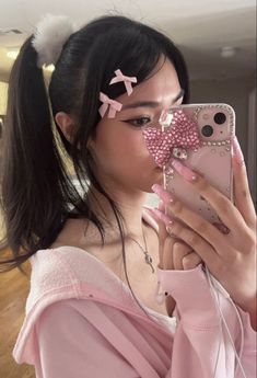 a woman taking a selfie with her cell phone and pink bow hair clip in front of her face