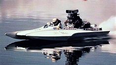 a man riding on the back of a white boat across a lake next to a red buoy