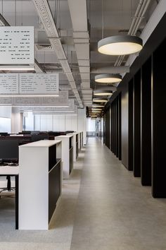 an empty office space with desks and hanging signs on the wall above them, along with black filing cabinets