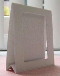 a white square frame sitting on top of a pink floor next to a window and door