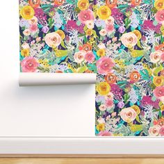 a wall with flowers on it next to a roll of paper and a white frame