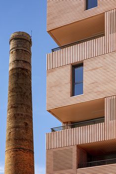 an old brick chimney in front of a tall building with balconies on it