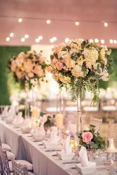 the table is set with flowers, candles and place settings for guests to sit at