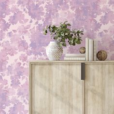 a vase filled with flowers sitting on top of a wooden cabinet next to a bookshelf