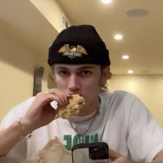 a young man is taking a selfie with his cell phone while eating food from a paper bag