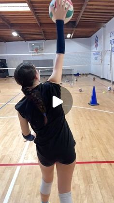 a woman in black shirt and knee high socks holding a volleyball on top of a hard wood floor