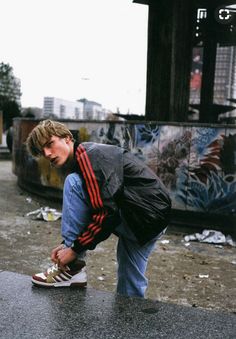 a young man crouches down to pick up his skateboard