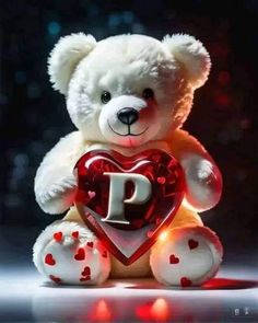 a white teddy bear holding a heart with the letter p on it's chest