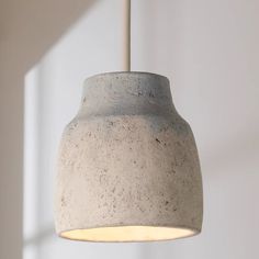 a concrete light hanging from a ceiling in a room with white walls and flooring