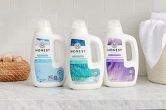 three gallon jugs of honest liquid sitting on a countertop next to a basket