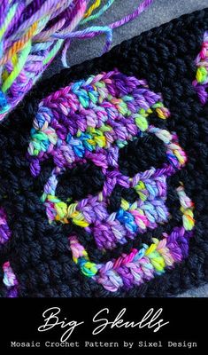 a crocheted bag with a smiley face on it and some yarn next to it