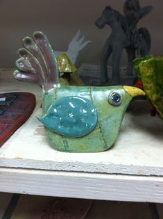 a ceramic bird sitting on top of a wooden table next to other figurines