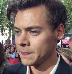 a close up of a person wearing a suit and tie with people in the background