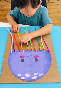 a young boy sitting at a table working on an art project with colored pencils