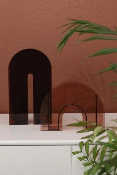 the letter m is made out of glass and sits on a table next to a potted plant