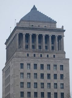 a very tall building with many windows and columns on it's sides in the city