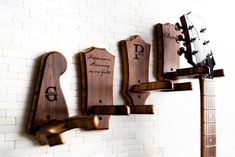 three guitars are mounted to the wall with their names on them, and there is also a guitar rack