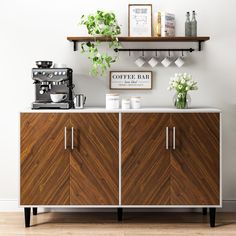 a coffee bar with wooden cabinets and white flowers in vases on the shelf above it