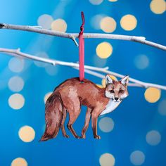 a red fox ornament hanging from a clothes line with lights in the background