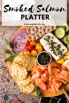 a platter with smoked salmon, crackers, cucumbers and olives