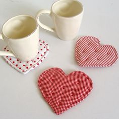 three heart shaped napkins sitting on top of a table next to two coffee mugs