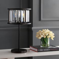 a vase with flowers on top of a table next to a book and candle holder