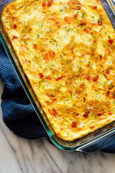 an egg casserole in a glass dish on top of a blue towel next to a fork