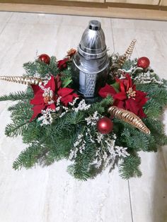 a christmas wreath with poinsettis, pine cones and other decorations on the floor