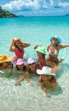 a group of women in the water wearing hats and bikinis on their heads are posing for a photo