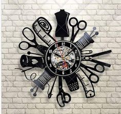 a black clock with scissors and combs on the face against a white brick wall