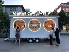 three people standing in front of a food truck with lights on it's side