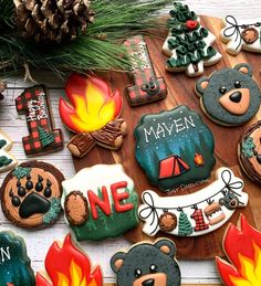 some decorated cookies on a wooden table with pine cones and fir trees in the background