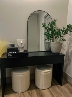 a black table with two stools and a mirror on the wall in front of it