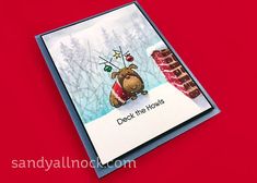 a close up of a card on a red surface with trees and snow in the background