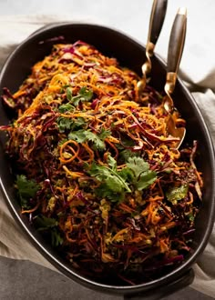 a bowl filled with shredded carrots and cilantro on top of a table